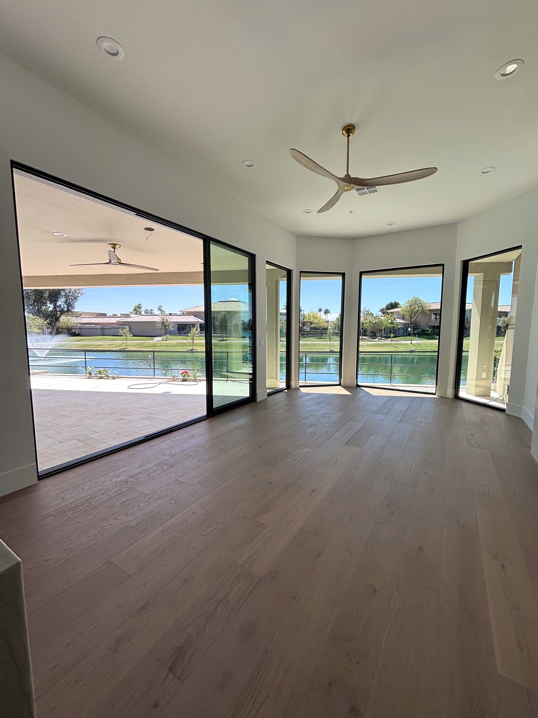 Great room with a corner wall of black-framed sliding glass doors facing a lake