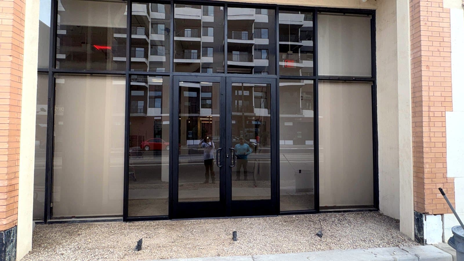 Commercial storefront with black-framed double glass entry doors and transom