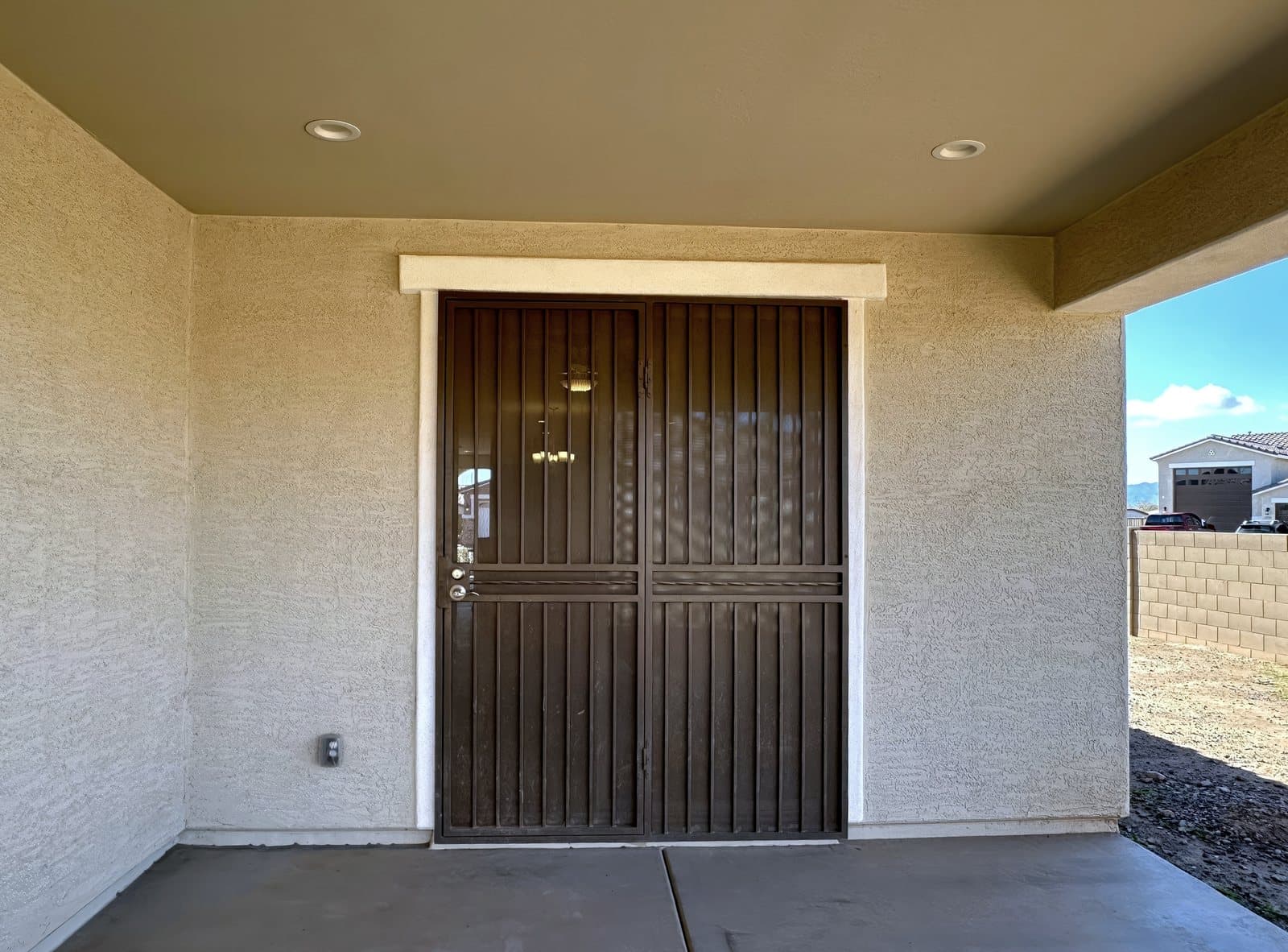 Bronze double security door installed at a covered entry